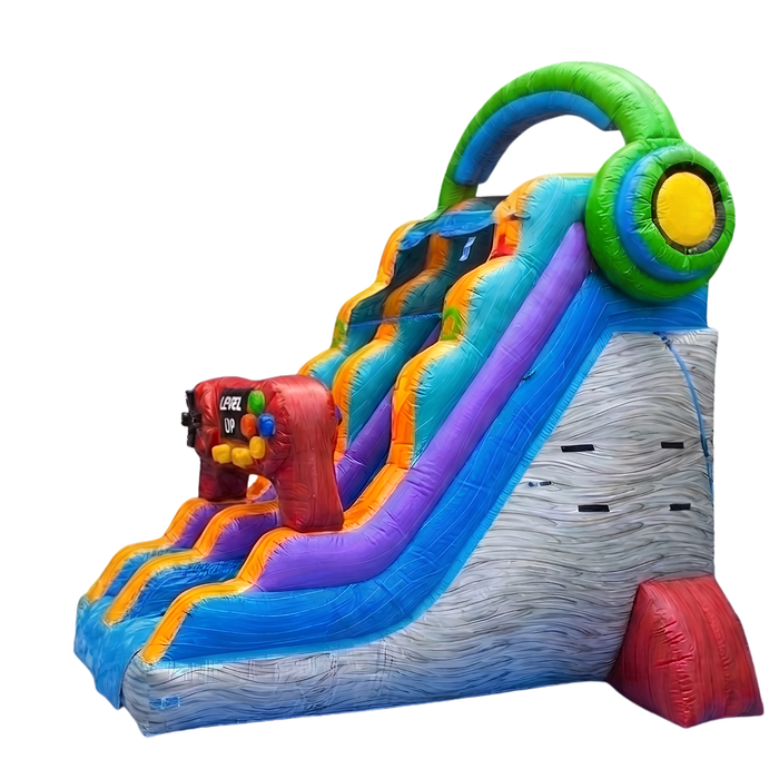 Studio product photo of the 18 foot Game Over wet and dry water slide from a rear three-quarter angle on a white background, showing the gray rock-textured back tower, green headphone topper, and dual slide lanes.
