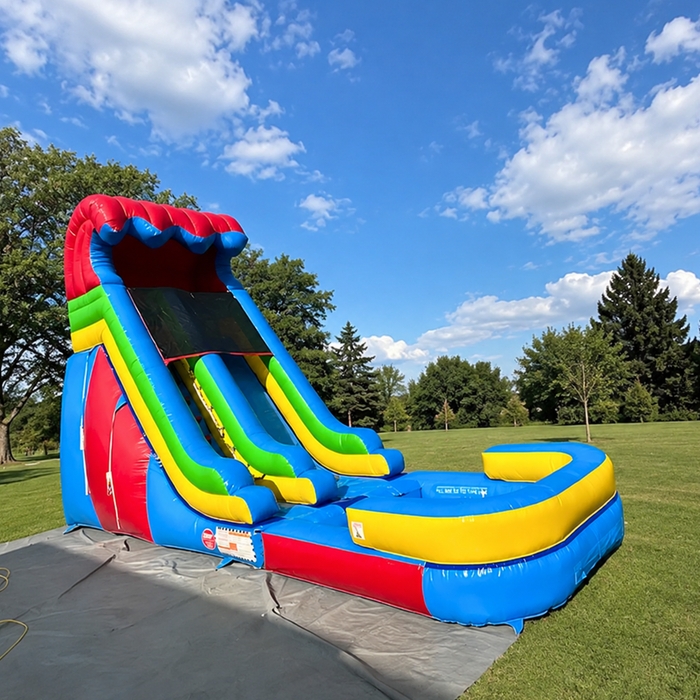 18' Rainbow slide set up on grass with a grey tarp under. Blue Sky