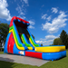 18' Rainbow slide set up on grass with multiple colors including blue, red, yellow, and green, set up outdoors on a grassy lawn under a bright blue sky with clouds.
