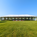 Beyond Tent 20x60 Classic Series West Coast Frame Tent setup on grass with white Cathedral window sidewalls and a wood dance floor visible inside