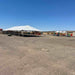 40x100 Classic Series Frame Tent frame is set up on a dusty, open desert ground under a clear blue sky. Smaller tents and equipment are visible in the background.