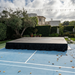 Beyond tent 4'x4' Portable Stage Platform | Heavy-Duty Commercial
 set up on a tennis court with black skirt and outdoor setting. Sunny day with leafs on the ground. 