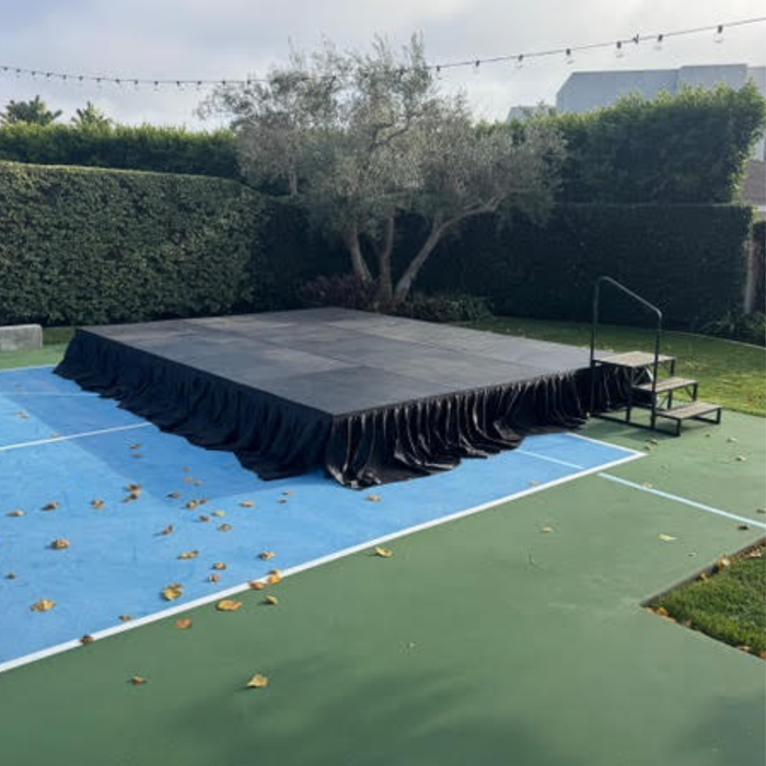 Beyond tent 4'x4' Portable Stage Platform | Heavy-Duty Commercial
set up on a tennis court with green and blue surface, surrounded by hedges and trees.