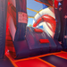 Inside the American Titan Wet and Dry Combo: navy climbing ramp with red handholds, slide safety rules sign, red and navy bounce floor, white star walls and mesh roof netting