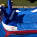 Close-up of the American Titan Wet and Dry Combo splash pool landing, blue marble vinyl with white and red trim, commercial safety label, slide end and flag holders set up on a blue tarp