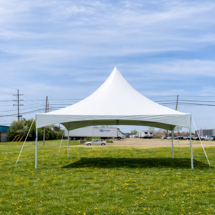 A white 20x20 High Peak Frame Party Tent set up on a green grass field with yellow wildflowers, featuring a sharp center peak and open sides.