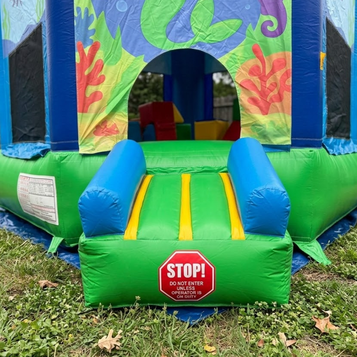 Colorful inflatable bounce house with a 'STOP!' sign on grass