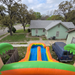 Inflatable water slide in a residential area with a house and blue van in the background Slide view. 