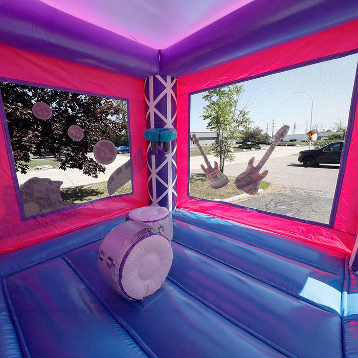 Second interior view of the KPOP Combo bounce chamber showing pink and purple interior walls, a basketball hoop in the center, and large finger-proof mesh netting windows on the sides allowing natural light in and giving supervisors clear visibility into the bounce area from outside. Asphalt surface visible through the mesh.