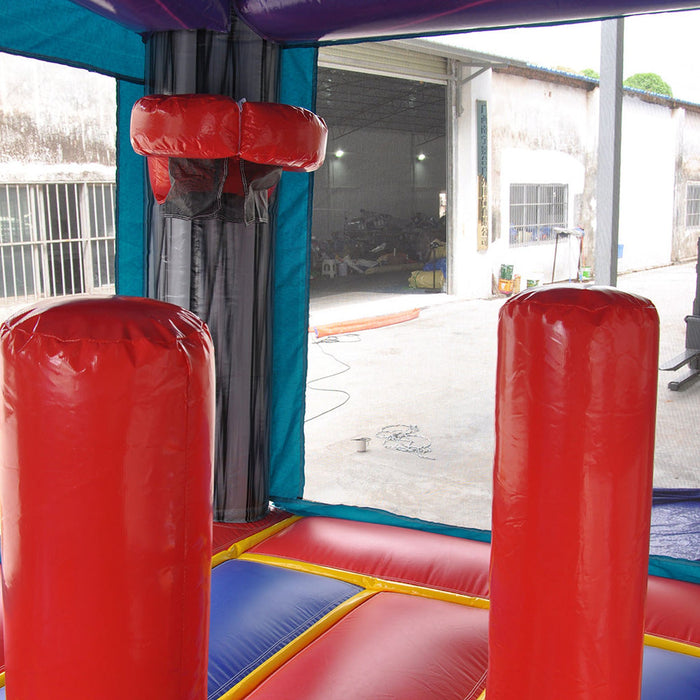 Game Over Wet & Dry Bounce House Combo with Slide, interior view showing red padded obstacle pillars and mesh netting inside the play area, with a manufacturing warehouse visible through the open mesh window in the background