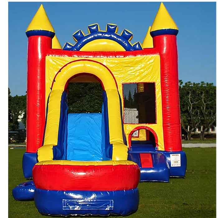 Outdoor setup of the Rainbow Play Wet & Dry Unisex Combo inflatable. View of the commercial-grade castle design in red, blue, and yellow with a front-facing water slide, safety entrance, and yellow turret towers on a grassy lawn