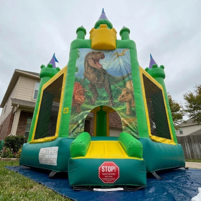 Dino-Dome Commercialinflatable bounce house on a grassy area with a house in the background. Angulo Contrapicado. 