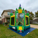 Dino-Dome Commercial themed inflatable bounce house on a grassy lawn in front of a house.