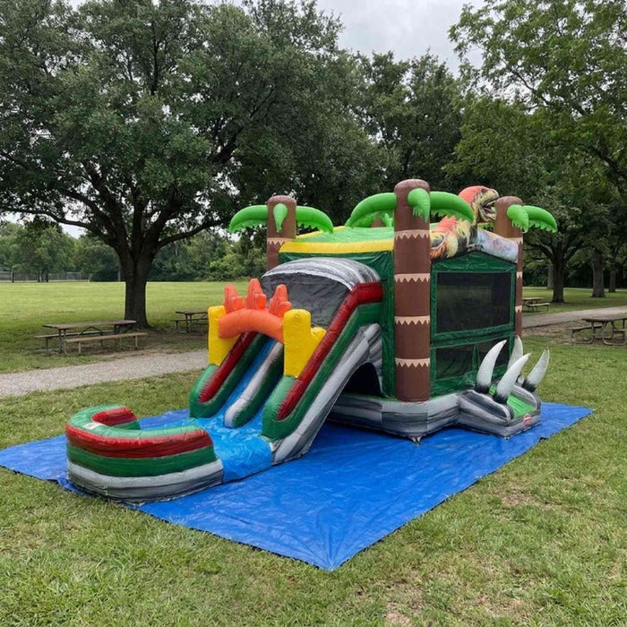 Beyond Tent Dino Stampede Bounce House Combo Wet & Dry set up on grass in a park setting with picnic tables and mature trees in the background