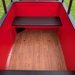 The back of a red trackless Frontier Train featuring a dark brown padded bench seat, a wood-look laminate floor, and red metal walls.