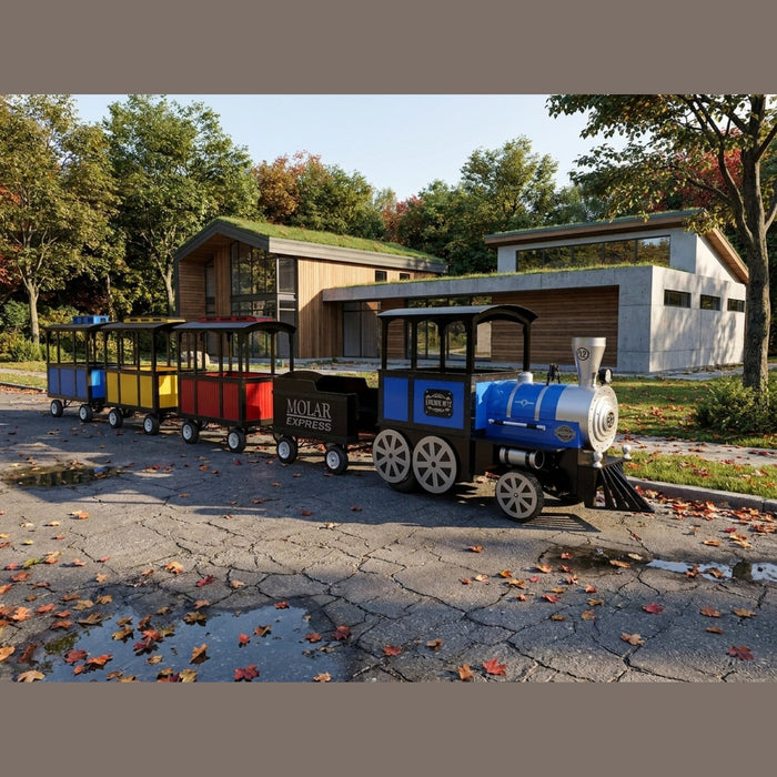 Frontier Trackless Train   (blue, yellow, red, black) parked outdoors on a paved road in front of a modern building with a green roof.