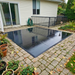 Beyond Tent Glossy Black Commercial Dance Floor installed on a paver patio, high-shine reflective black surface wet from rain, next to a house with a black metal railing