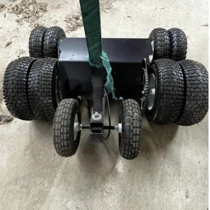Industrial IRM-2000 inflatable rolling machine with six heavy-duty treaded tires and drive chain, positioned on a concrete warehouse floor for rolling commercial bounce houses.