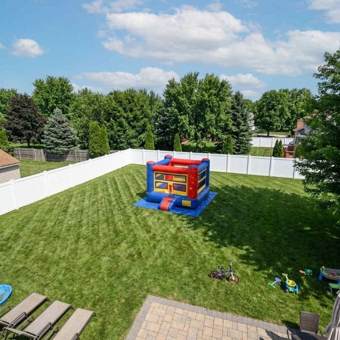 Beyond Tent Knockout Zone 15ft Commercial Boxing Bounce House, aerial drone view of the bounce house set up in a large fenced backyard with a patio and kids' toys nearby