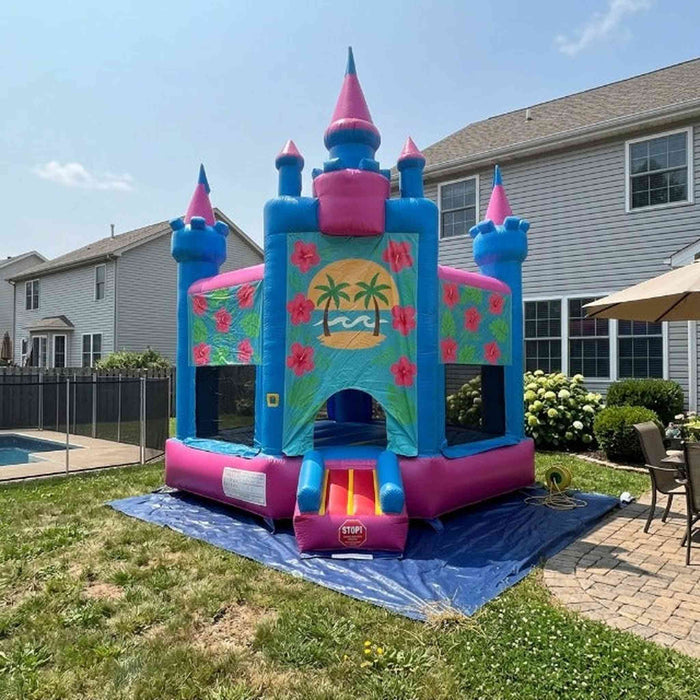 Beyond Tent Lightweight Hawaiian Castle Bounce House with Blower set up in a backyard near a pool, patio furniture, and hydrangea bushes, with houses in the background