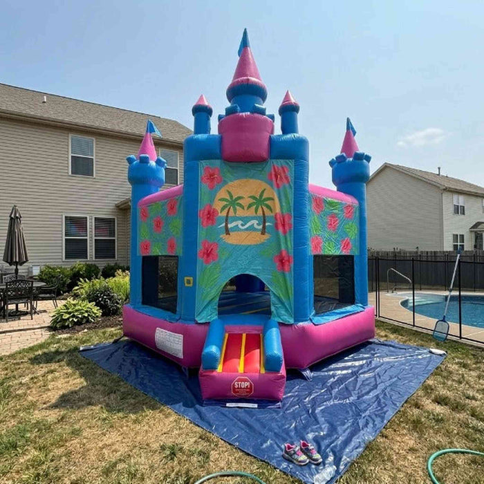 Beyond Tent Lightweight Hawaiian Castle Bounce House with Blower set up in a backyard next to a swimming pool, with a privacy fence and houses in the background