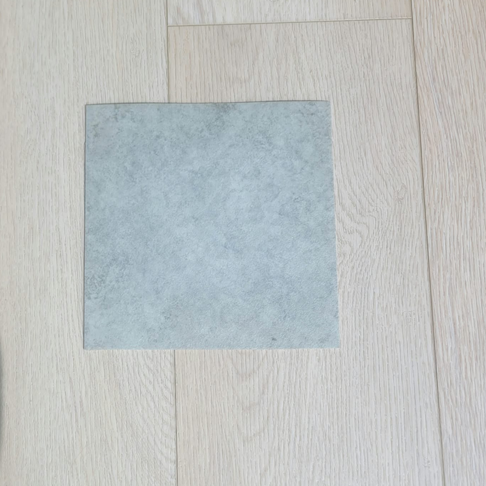 Natural Grey Vinyl Flooring | Commercial Grade
tile or flooring material placed on a light beige wood plank surface.