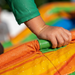 Child's hand holding onto a colorful inflatable slide with a blurred background
