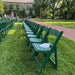 Resin Folding Chair Green - 1100 lb Capacity arranged on a grassy campus lawn in front of a large stone building with ivy-covered walls and trees.