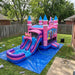 Royal Princess Bounce House Combo Wet &amp; Dry — Commercial Grade set up on a blue tarp in a backyard with grass, trees, and a wooden fence.