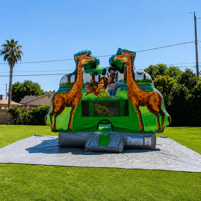 Beyond Tent Rumble Bounce House 13x13 with Blower set up on a green lawn with a palm tree in the background, giraffe toppers and jungle animal mural, sunny day