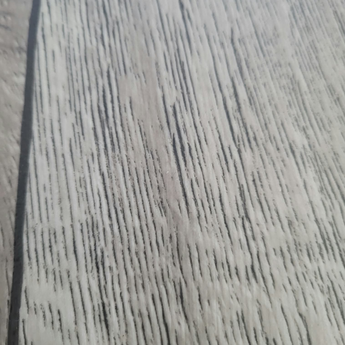 Close-up texture detail of Beyond Tent Silver Oak commercial-grade vinyl flooring, showing the realistic wood-grain surface pattern