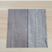 Beyond Tent Silver Oak commercial-grade vinyl flooring tile sample placed on a light wood-tone surface for color comparison