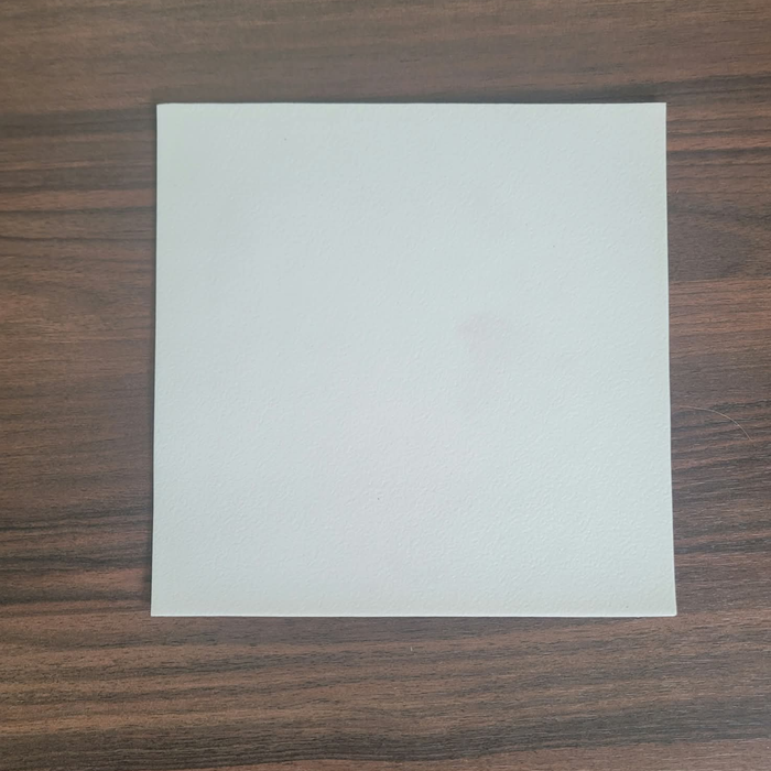 Matte White Rolled Vinyl Flooring sample swatch close-up on a dark walnut wood table, showing the matte surface texture