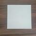 Matte White Rolled Vinyl Flooring sample swatch close-up on a dark walnut wood table, showing the matte surface texture