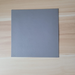 Solid  gray textured tile vinyl placed on a light wood grain surface. Beyond Tent exclusive picture. 