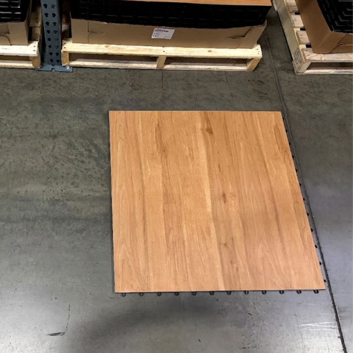 Exclusive beyond Tent Tile picture of a Timber Tile  with a natural oak grain pattern, shown from above on a concrete warehouse floor next to pallets.