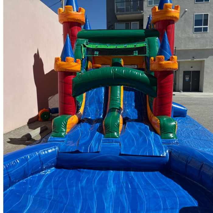 Twin Tower Dash wet and dry inflatable combo side view – green enclosed water slide leading into inflatable splash pool, castle bounce house with dual towers in background