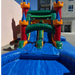 Twin Tower Dash wet and dry inflatable combo side view – green enclosed water slide leading into inflatable splash pool, castle bounce house with dual towers in background