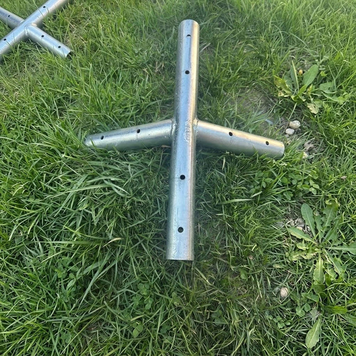 Beyond Tent West Coast Frame Tent Ridge Crown Fitting, galvanized steel 5-way crown connector fitting laid on grass with a second fitting visible in the background