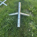 Beyond Tent West Coast Frame Tent Ridge Crown Fitting, galvanized steel 5-way crown connector fitting laid on grass with a second fitting visible in the background