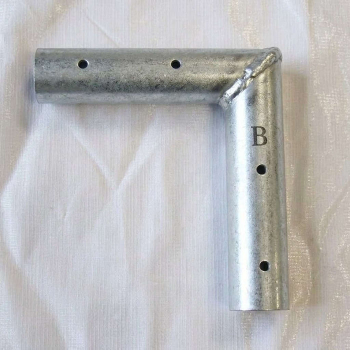 West Coast Frame Tent 2-Way Flat Tee Fitting , featuring a welded corner and a stamped letter 'B' on the vertical leg, displayed on a white textured fabric background.