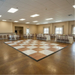 Large room with a checkered White Natural and Timber color dance floor and tables set up for an event.