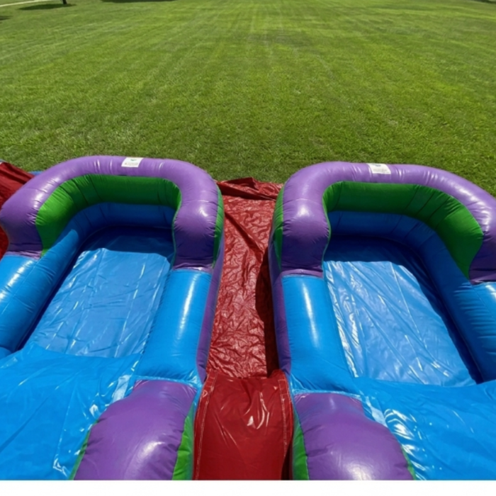 Top-down view of the Beyond Tent 13-foot Lightweight Violet Twin Slide showing the dual inflatable splash pools and red center slide lane, set up on a manicured grass lawn.