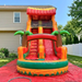 Alt Text: Beyond Tent 18-foot commercial Tropical Inflatable Water Slide with 3D palm trees and a wide landing pool, set up on a red protective ground tarp in a residential backyard with a white vinyl fence.