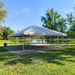 Exterior view of a Beyond Tent 30x40 Classic Series West Coast frame tent professionally installed on a stone paver patio overlooking a lake, demonstrating the structure's versatility on hard surfaces.