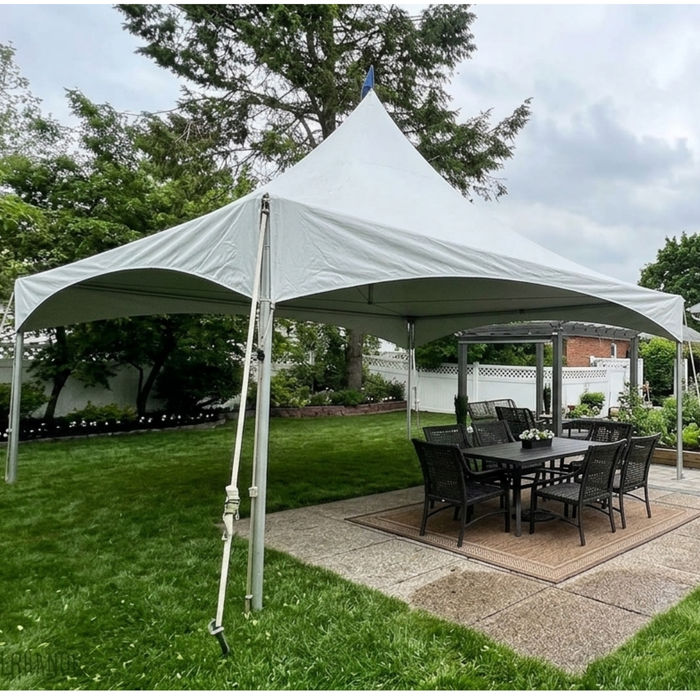 Commercial-grade 15x20 High Peak frame tent with a white tension canopy top, assembled over a backyard concrete patio with an outdoor dining table and chairs.
