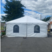 Commercial-grade white frame event tent with cathedral window sidewalls installed on an outdoor asphalt driveway under a partly cloudy sky.