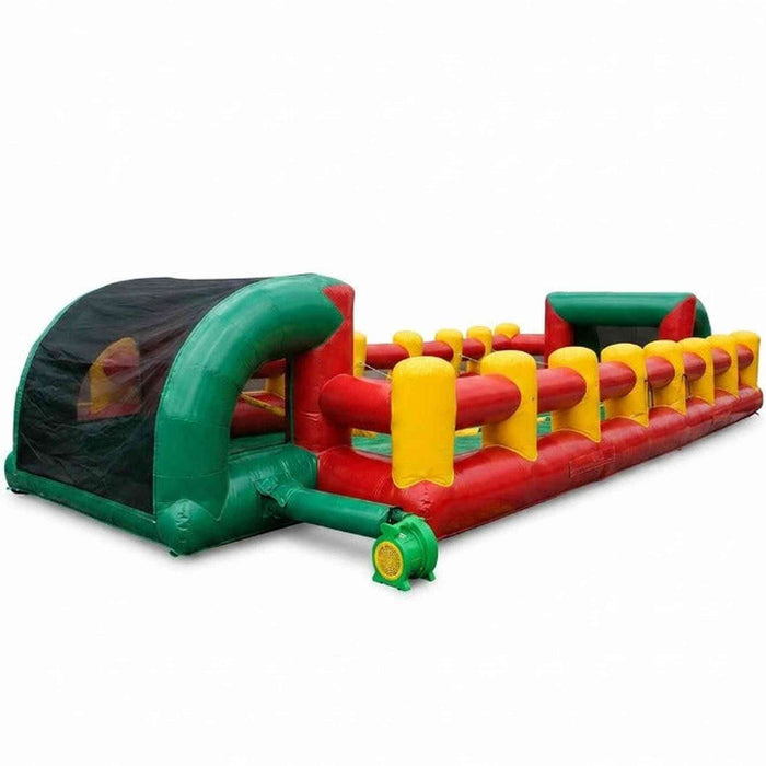 Full length view of a commercial inflatable human foosball interactive game showing yellow vertical support pillars, red and green vinyl walls, and the open goal netting end.