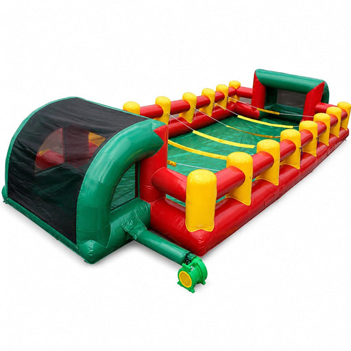 Commercial-grade inflatable human foosball interactive game with green, red, and yellow PVC vinyl construction, safety netting, and attached blower tube.