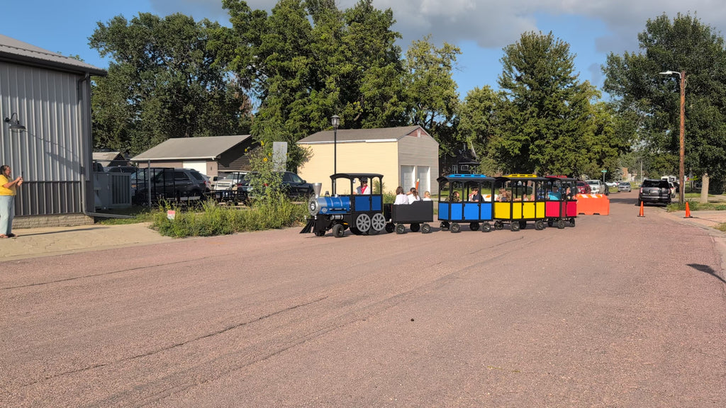 Frontier Gas Powered Trackless Train in action carrying passengers down a paved street at a festival. Beyond Tent Exclusive video. Product performance. 